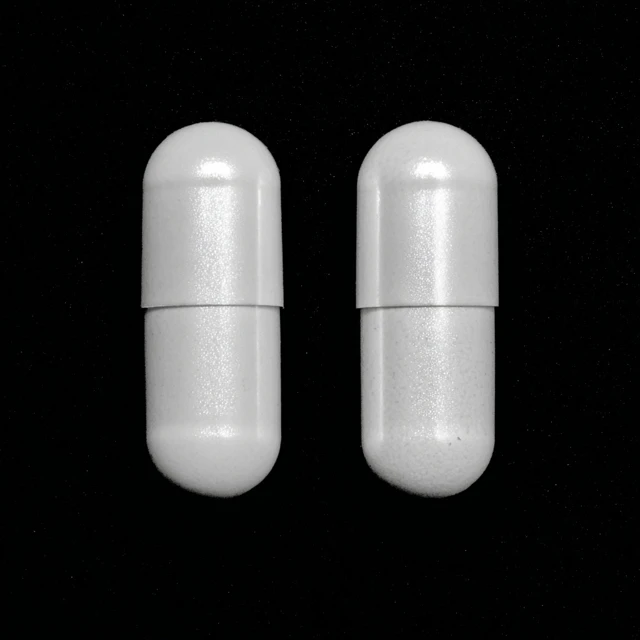 Two White Capsules on Pink Background