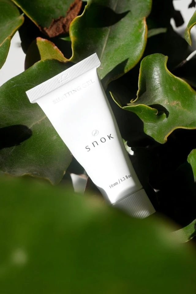 White Cosmetic Tube Surrounded by Leaves