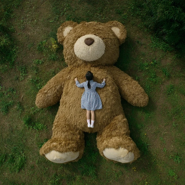 Girl and Giant Teddy Bear on Green Grass