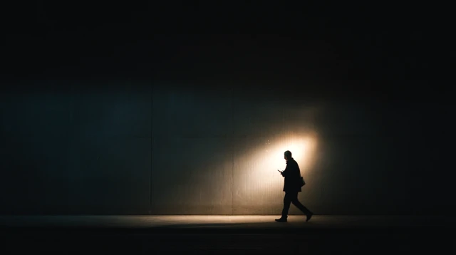Man in Dark Hallway Using Phone Light