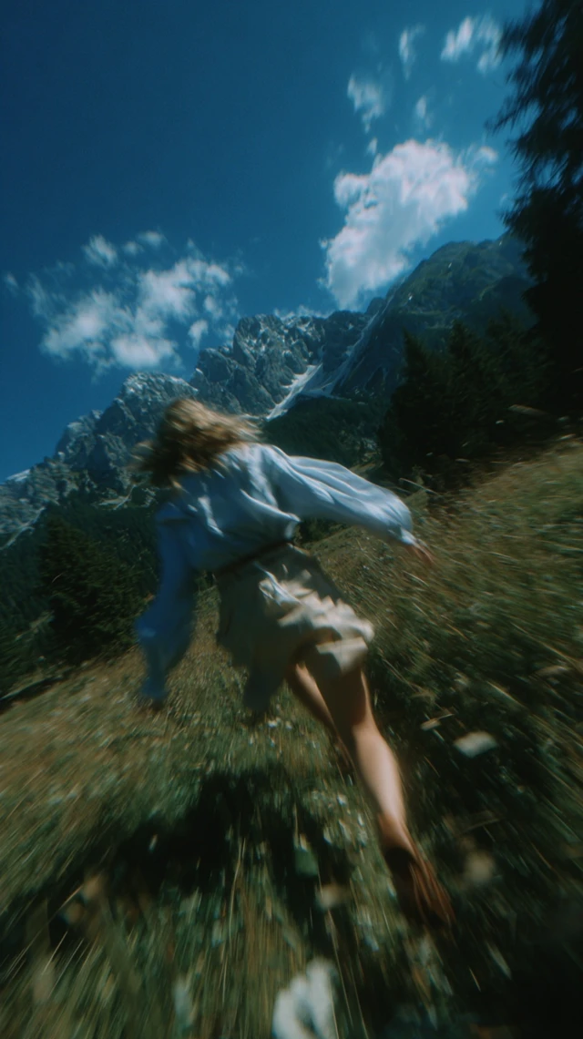 Woman Gliding Over Grass Mountains and Sky