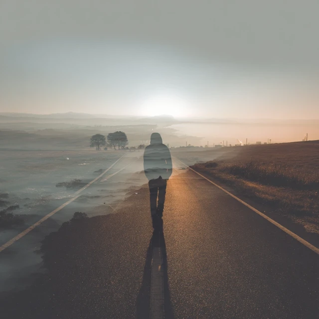 Person Walking on Road: Journey Towards the Light