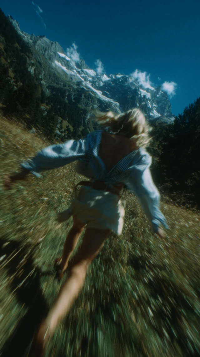 Woman Gliding Over Grass Mountains and Sky