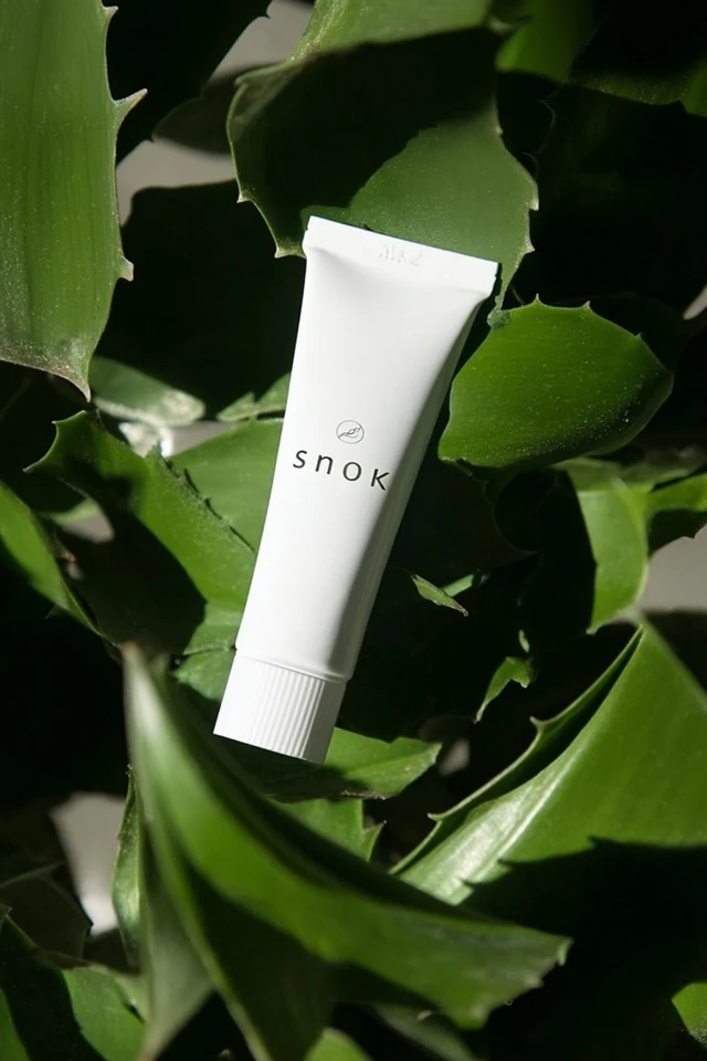 White Cosmetic Tube Surrounded by Leaves