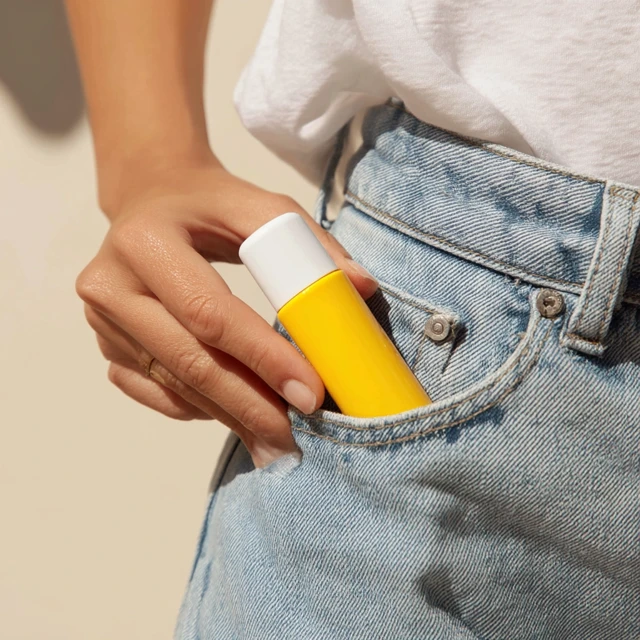 Woman Putting Yellow Bottle in Pocket